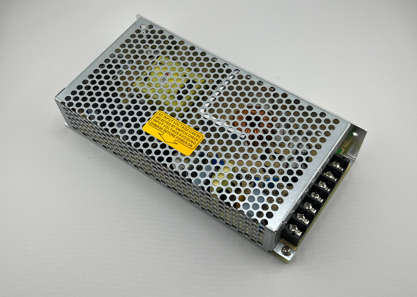 Rectangular metal power supply unit with a yellow label on a gray background