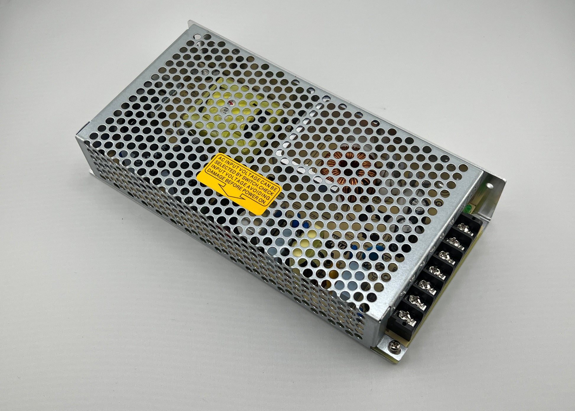 Rectangular metal power supply unit with a yellow label on a gray background