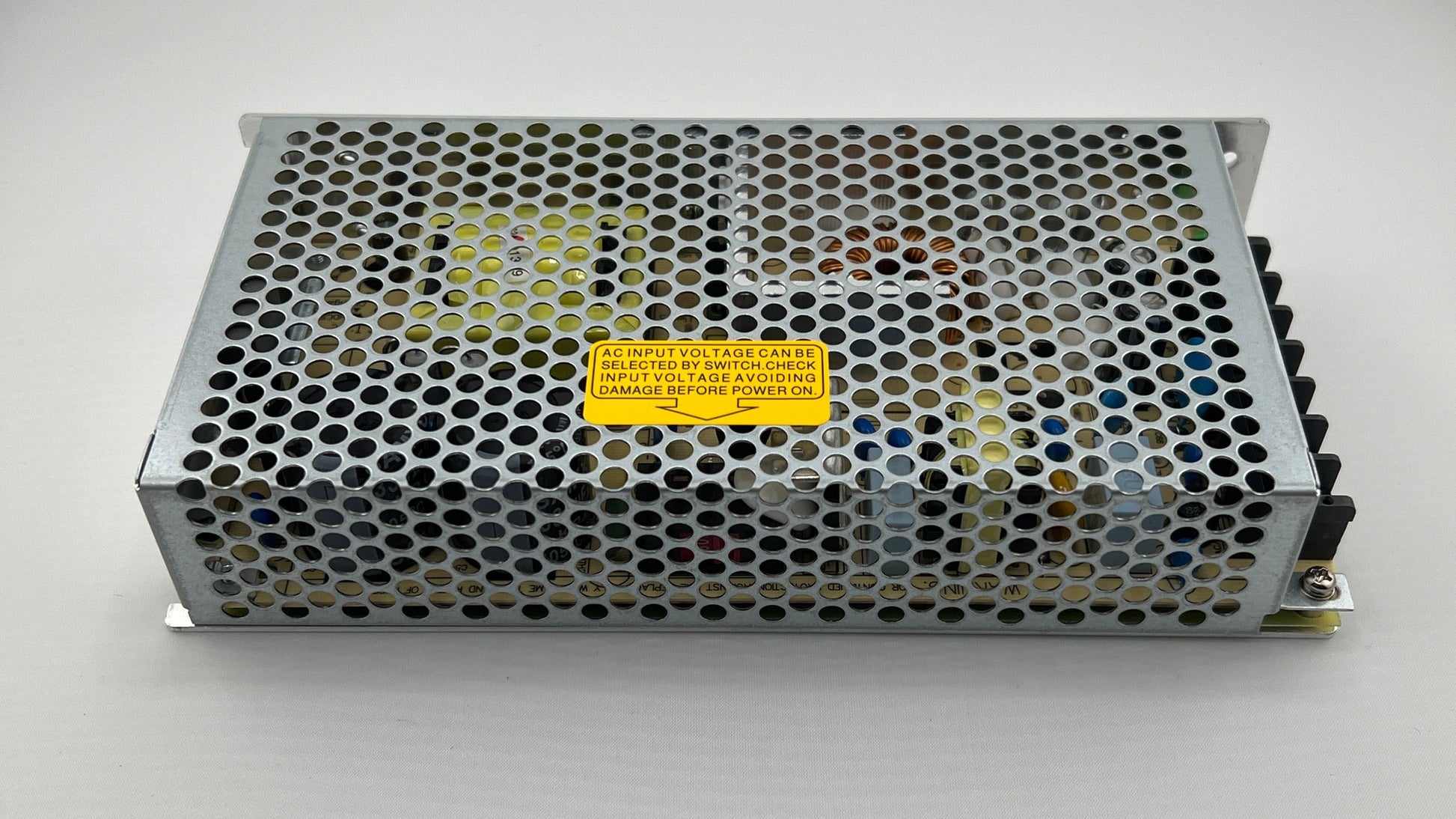 Metal power supply unit with a yellow label on a white background